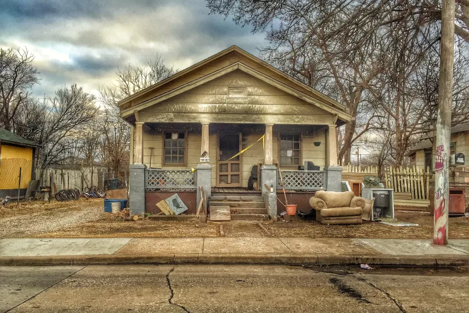 Old single-story home with porch in run-down condition